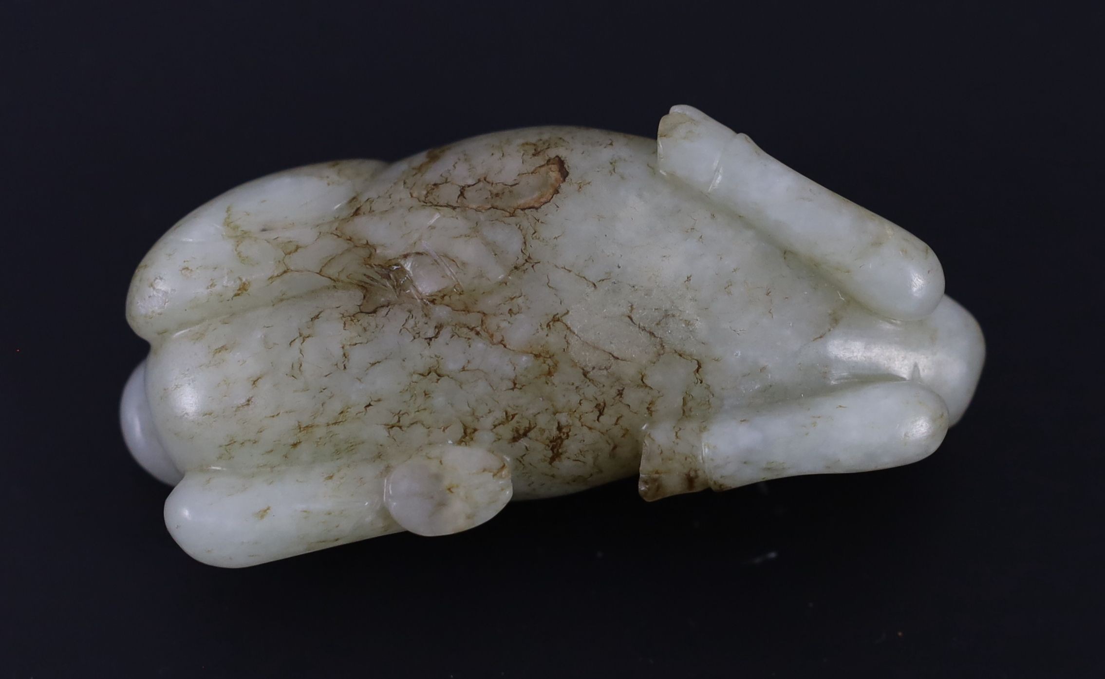 A Chinese Ming pale celadon and brown jade figure of a recumbent Buffalo, 16th/17th century, 8cm long